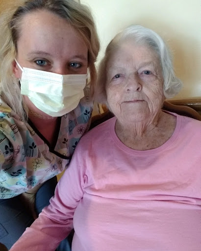 A caregiver smiling with an elderly woman, both enjoying a moment together.