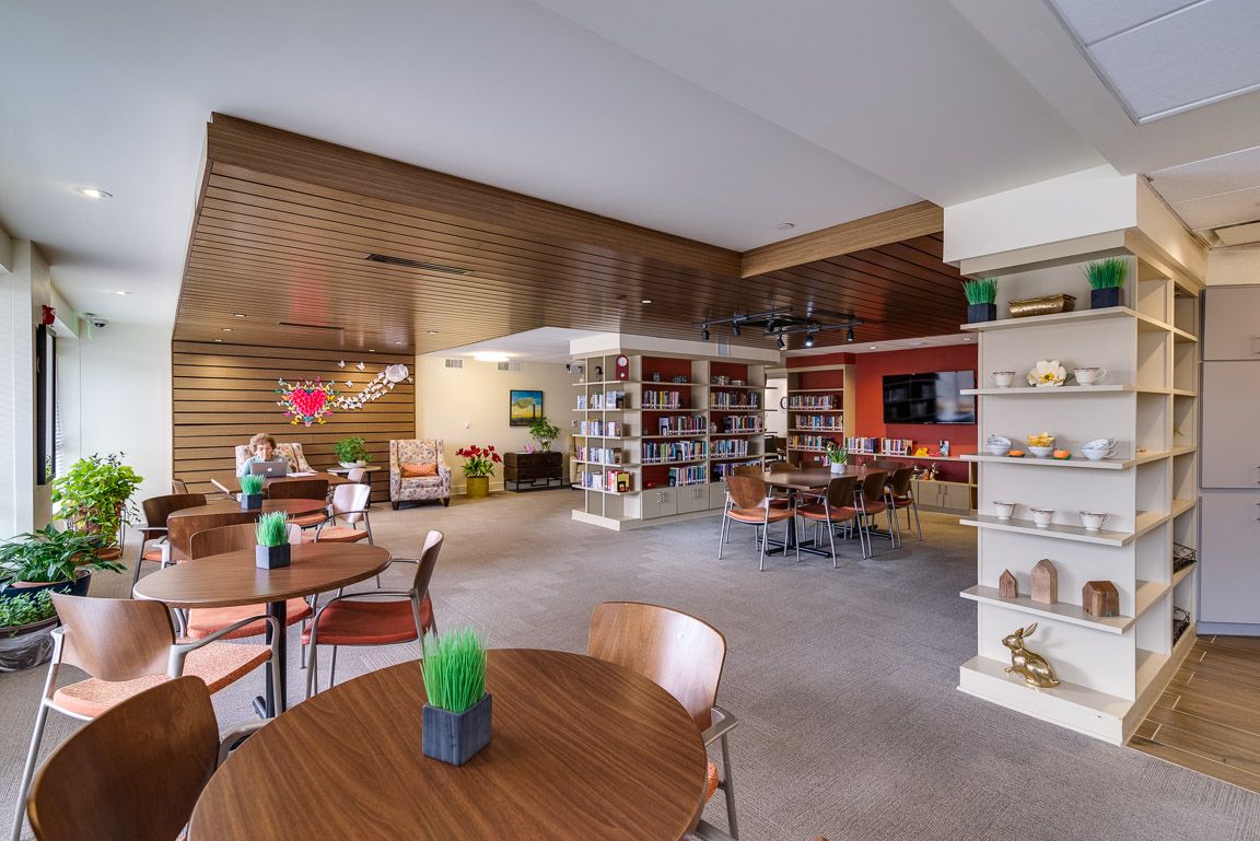 A cozy indoor cafe with tables, chairs, and bookshelves.