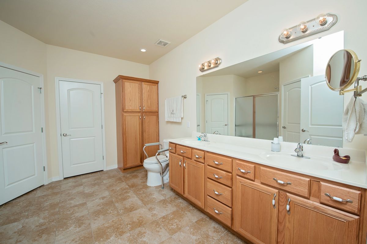 Spacious bathroom with a large vanity, mirror, and ample lighting.