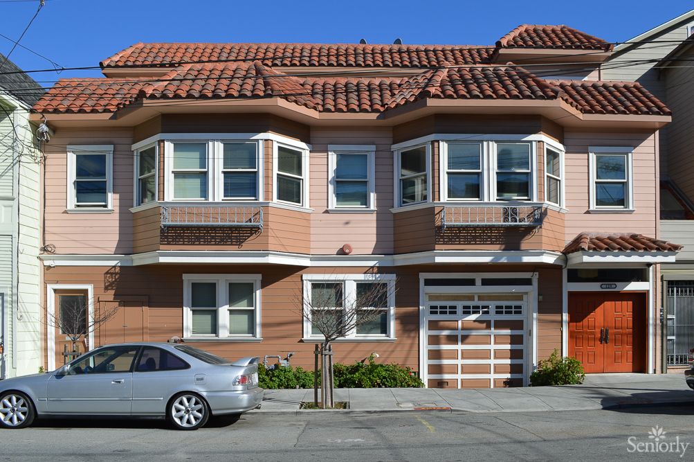 A residential house with a car parked in front and a garage entrance.