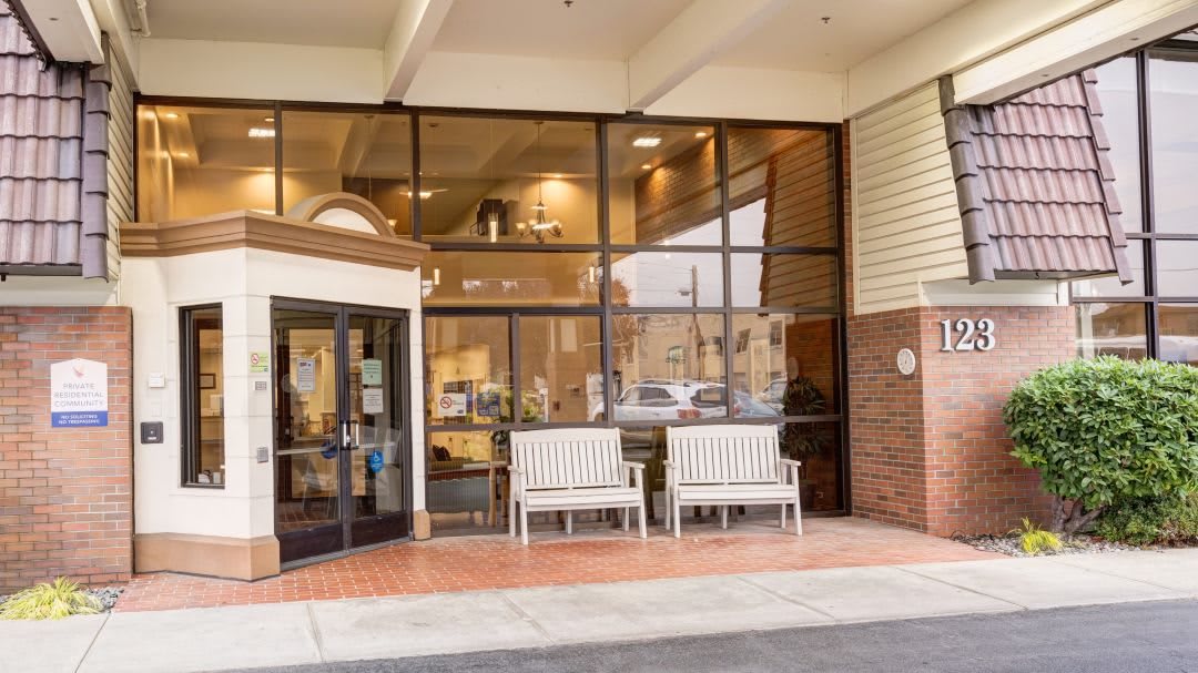 The entrance of a building featuring glass windows and benches outside.