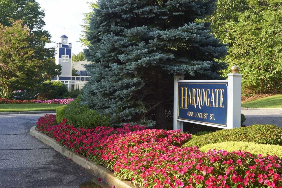Entrance to a residential complex with colorful flowers and a prominent sign.