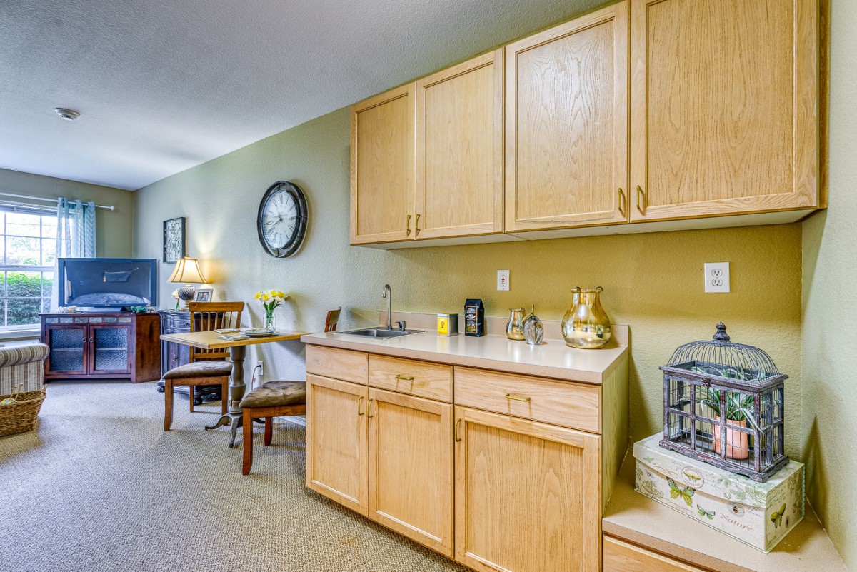 A cozy kitchenette with wooden cabinetry, a small dining area, and decorative items on the counter.