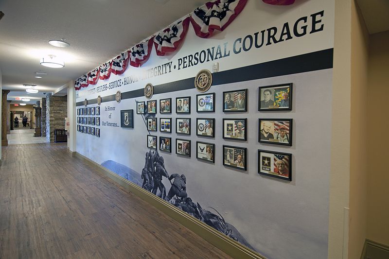 A hallway in a museum featuring a wall display dedicated to personal courage, adorned with patriotic banners and various artworks.