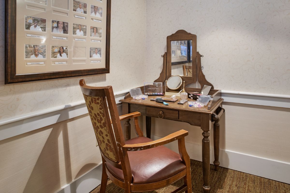 A cozy dressing table setup with a wooden chair and mirror, surrounded by various personal items.
