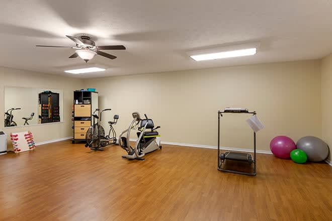A spacious home gym with exercise equipment and wood flooring.