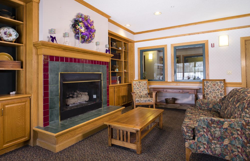 A cozy living room featuring a fireplace, wooden furniture, and decorative elements.
