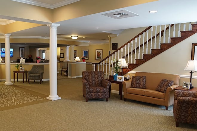 A spacious living room with comfortable seating, a staircase, and elegant decor.