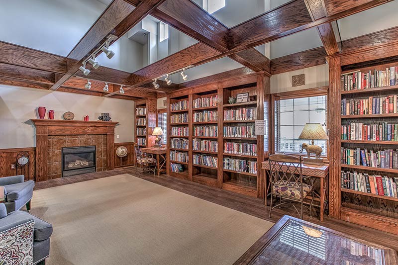 A cozy library with wooden bookshelves and a fireplace, perfect for reading.