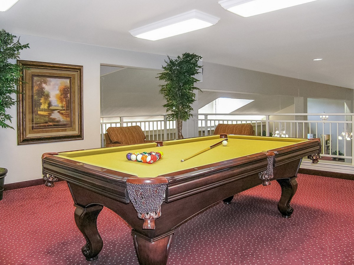A billiard table in a recreation room with cozy seating and decor.