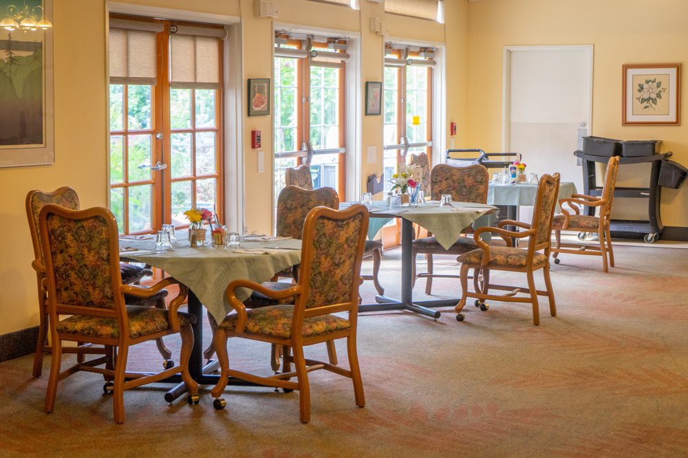 A cozy dining area with neatly arranged tables and chairs near large windows.