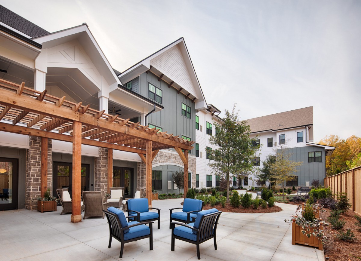 A modern building with a spacious outdoor patio featuring comfortable seating and landscaped surroundings.