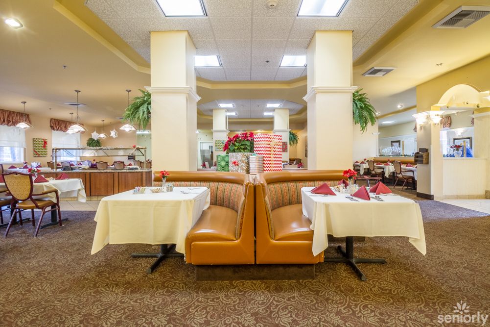 A well-lit restaurant interior featuring comfortable booths and neatly set tables.