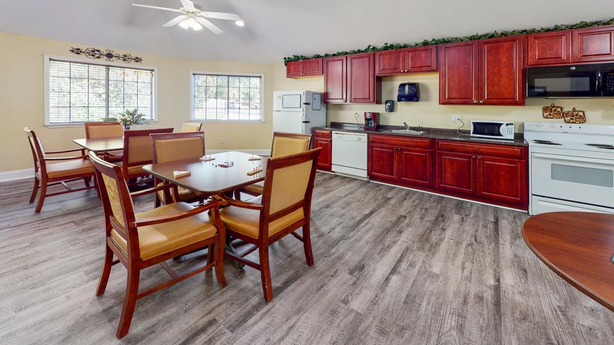 A modern kitchen with red cabinets and a dining area featuring wooden flooring and a ceiling fan.