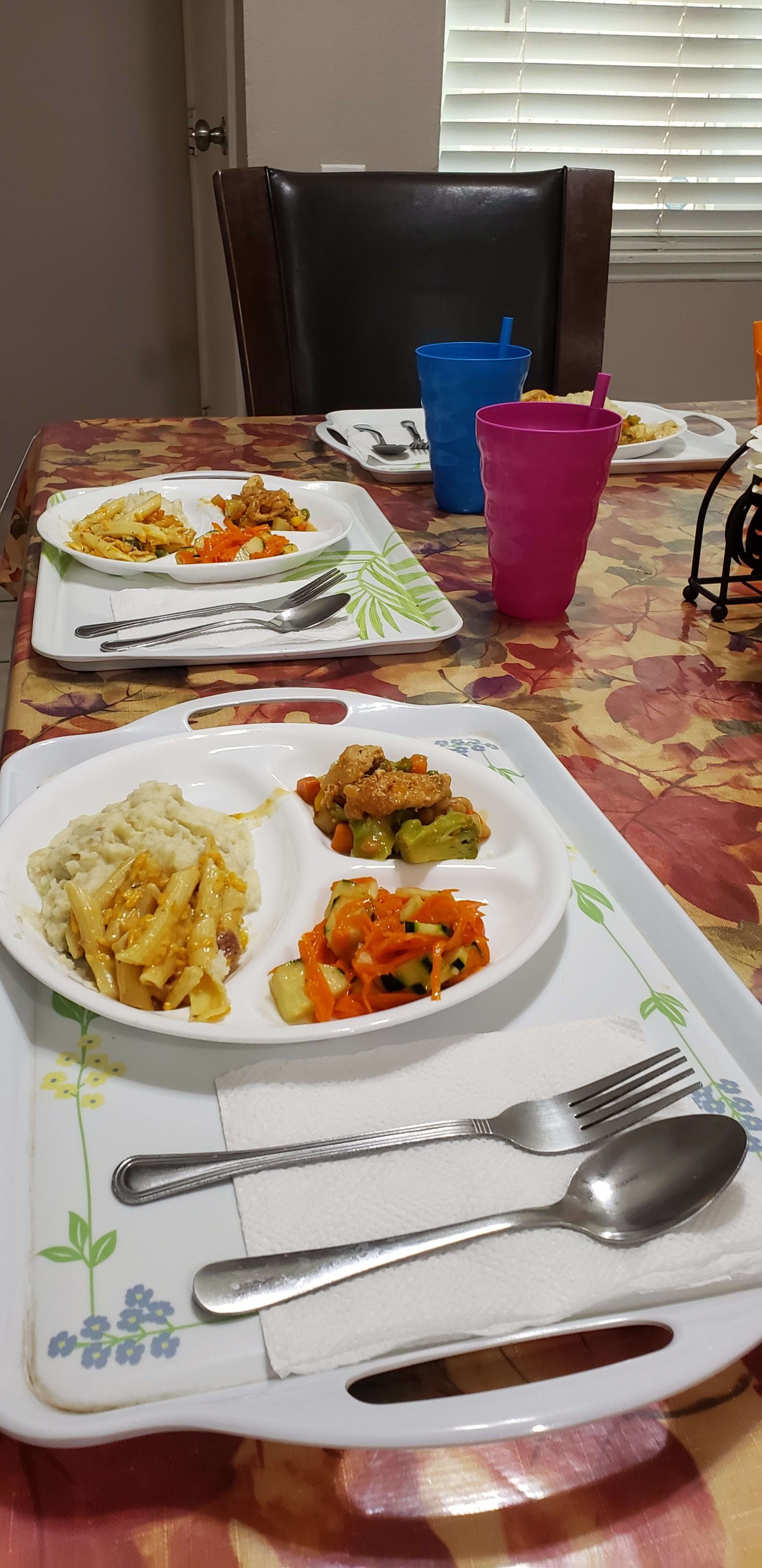 A dining table set with trays of food including vegetables and pasta.