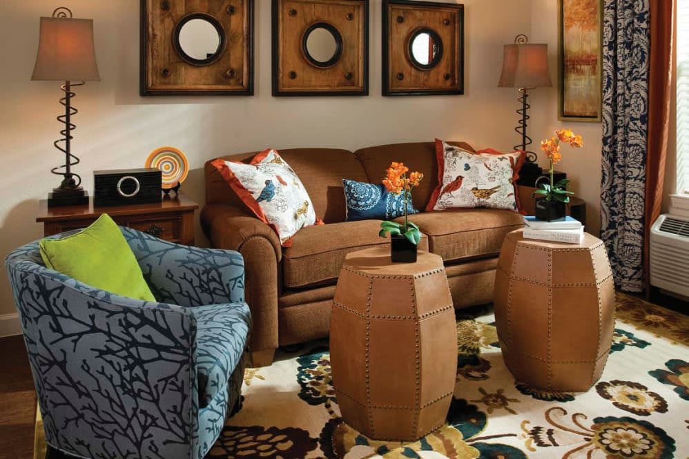 A cozy living room featuring a brown sofa, patterned armchair, and decorative pillows alongside circular wall art.