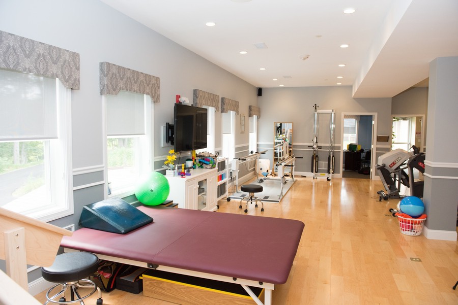 A well-equipped physical therapy clinic featuring treatment tables and exercise equipment.