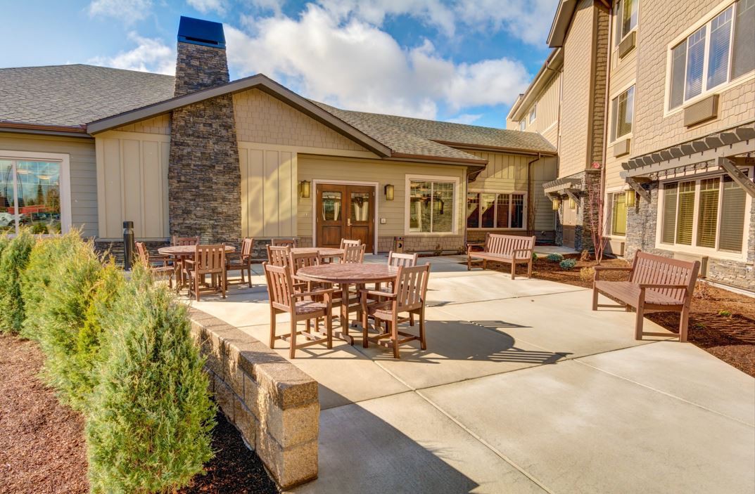 A sunny patio area with outdoor seating adjacent to a modern building.