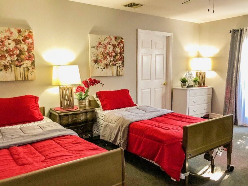 A cozy bedroom with two twin beds featuring red bedding, illuminated by stylish lamps on modern nightstands.
