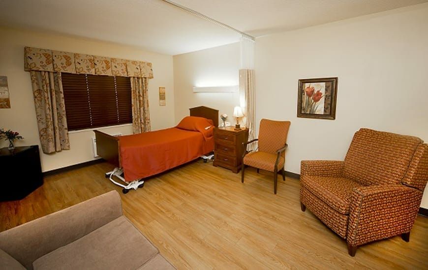 A cozy and well-furnished bedroom featuring a single bed, chairs, and warm lighting.