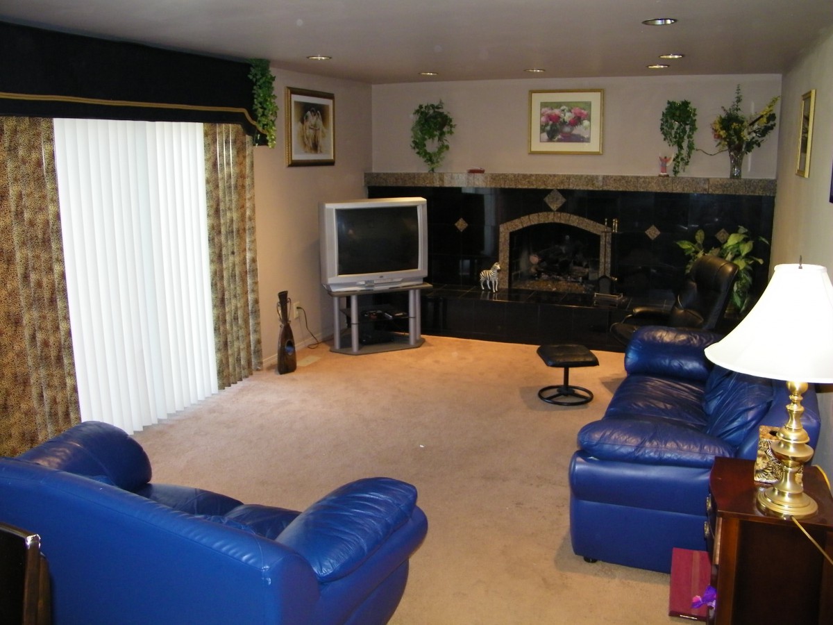 A cozy living room with blue leather furniture, a television, and a fireplace.