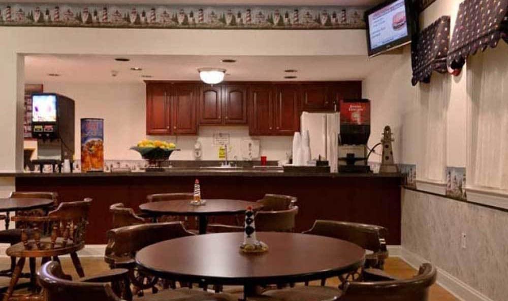A cozy cafe with round tables, chairs, and a kitchen counter in the background.