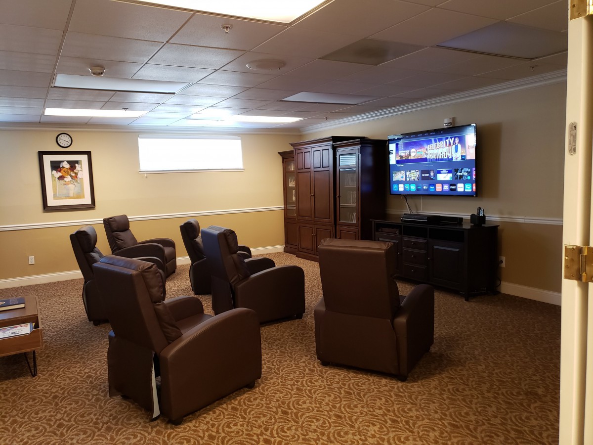 A cozy home theater setup with multiple recliner chairs facing a large screen TV.