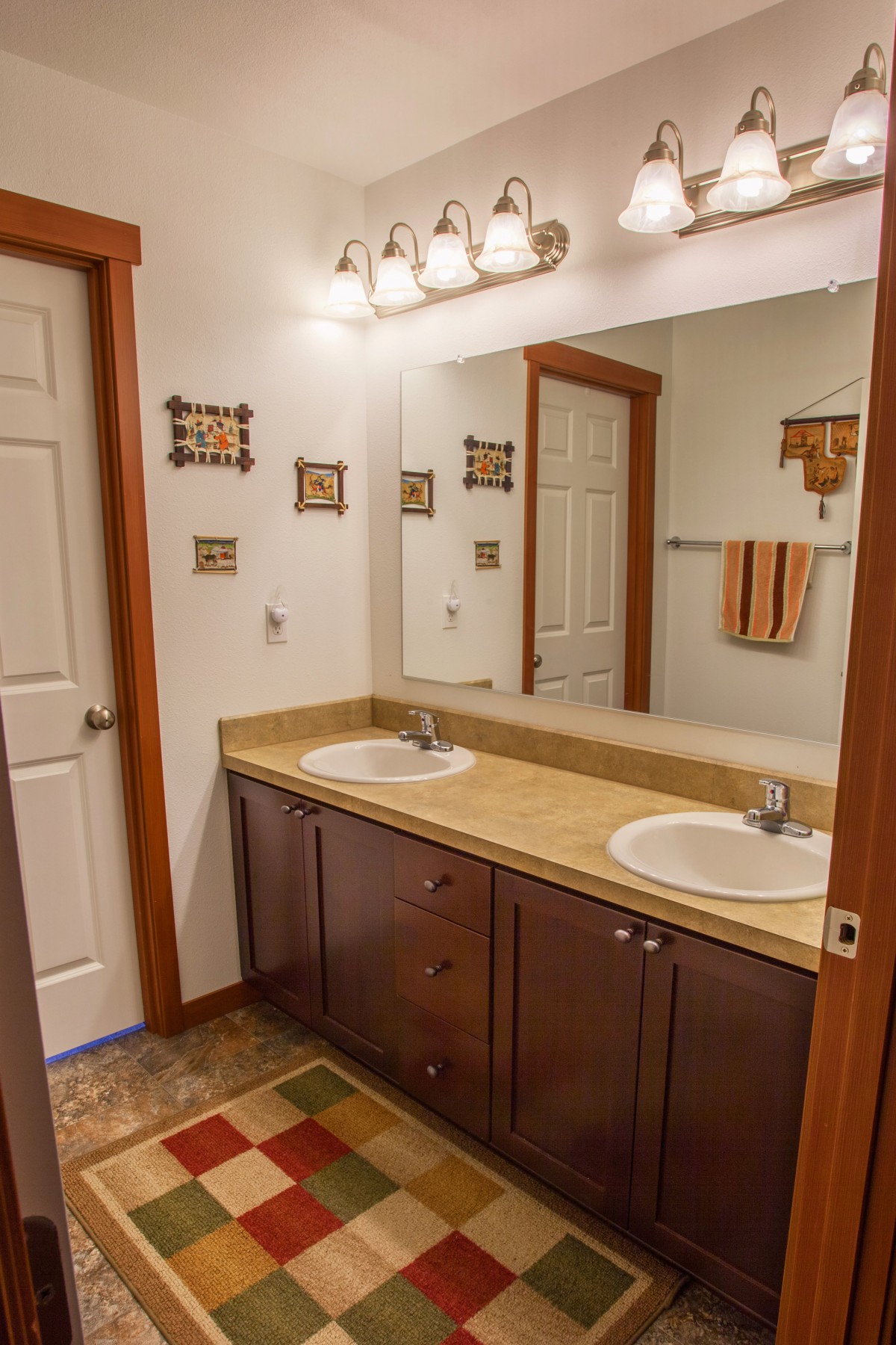 A spacious bathroom featuring a double sink vanity with a large mirror and elegant lighting.