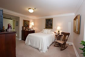 A cozy bedroom with a neatly made bed, side table lamps, and a rocking chair.