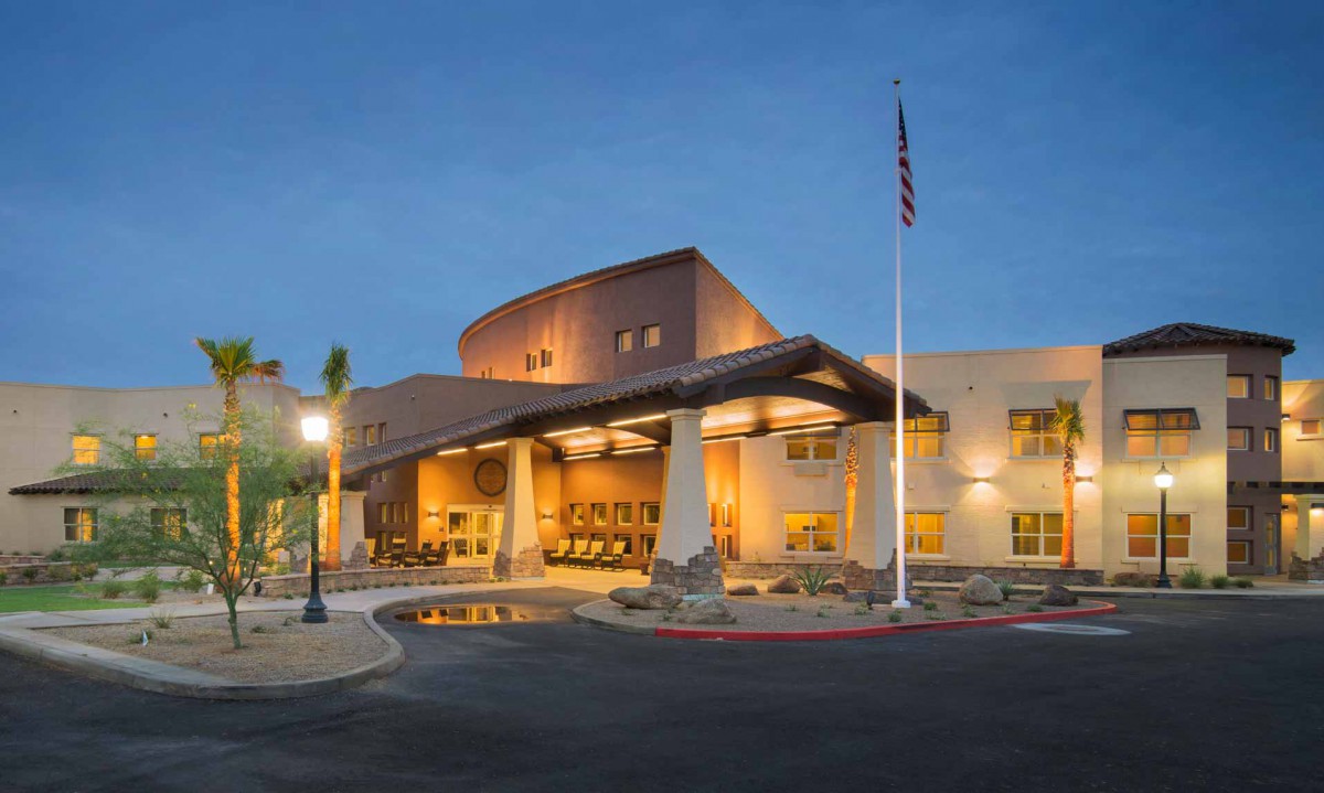 An illuminated building entrance with a flagpole during the evening.