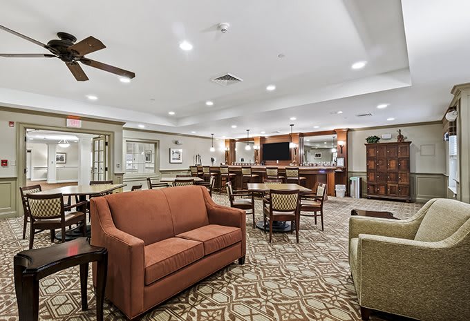 A spacious and elegantly decorated lounge area with comfortable seating, a patterned carpet, and a bar in the background.