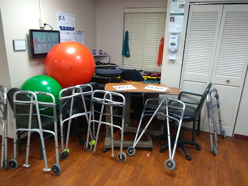 A therapy room equipped with various exercise tools including walkers and fitness balls.