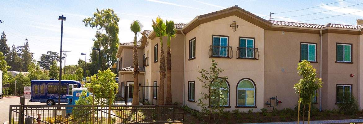 A residential building with palm trees in the foreground.