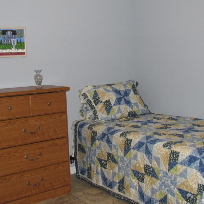 A minimalist bedroom with a single bed and wooden dresser.