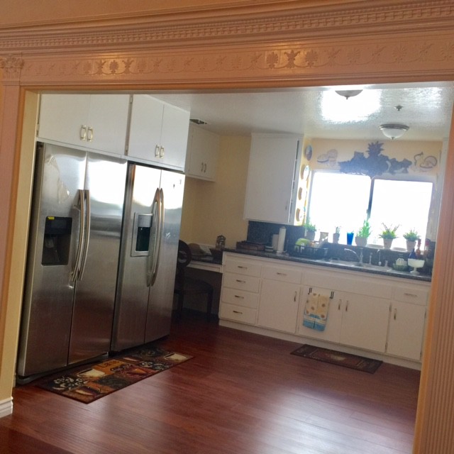 A spacious kitchen with stainless steel appliances and wooden flooring.