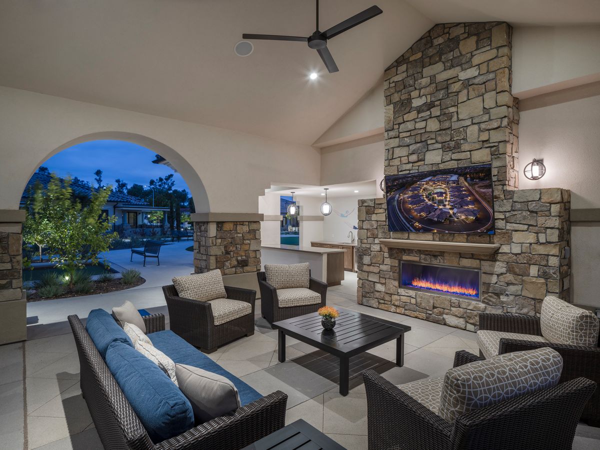A modern outdoor patio with comfortable seating and a stone fireplace, creating a cozy evening ambiance.