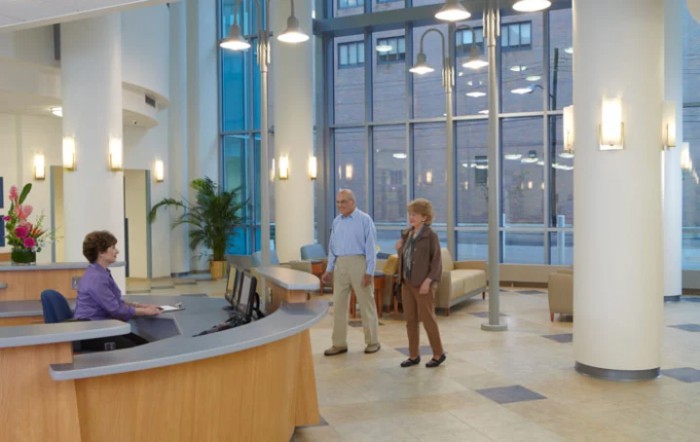 People standing in a modern lobby with comfortable seating and large windows.