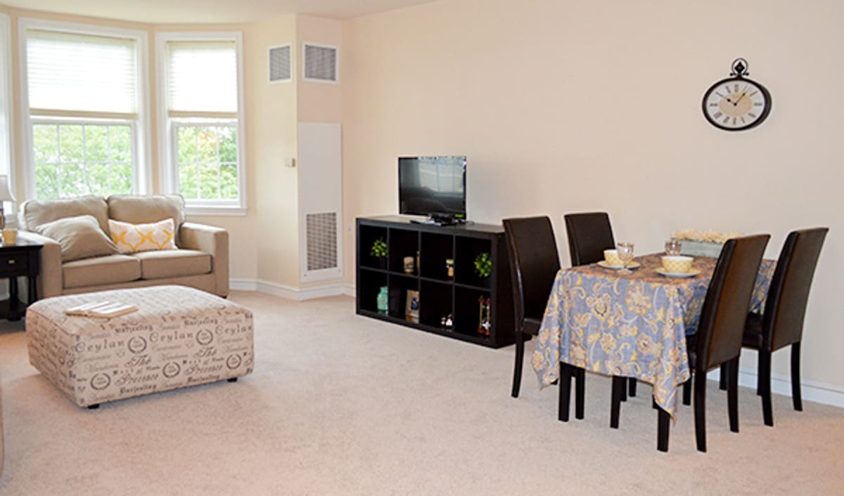 A cozy living and dining area with a sofa, TV, and table set.