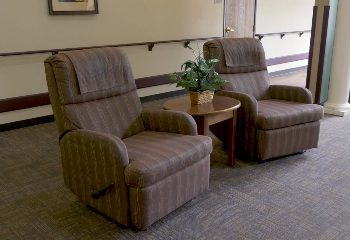 A cozy waiting area with two armchairs and a small table with a plant.