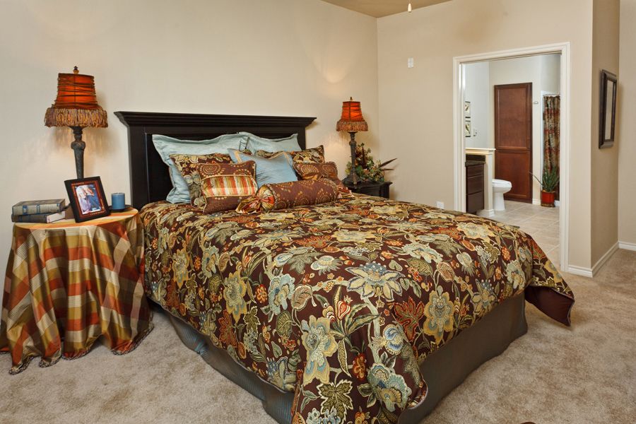 A cozy bedroom with a floral-patterned bedspread and decorative pillows.