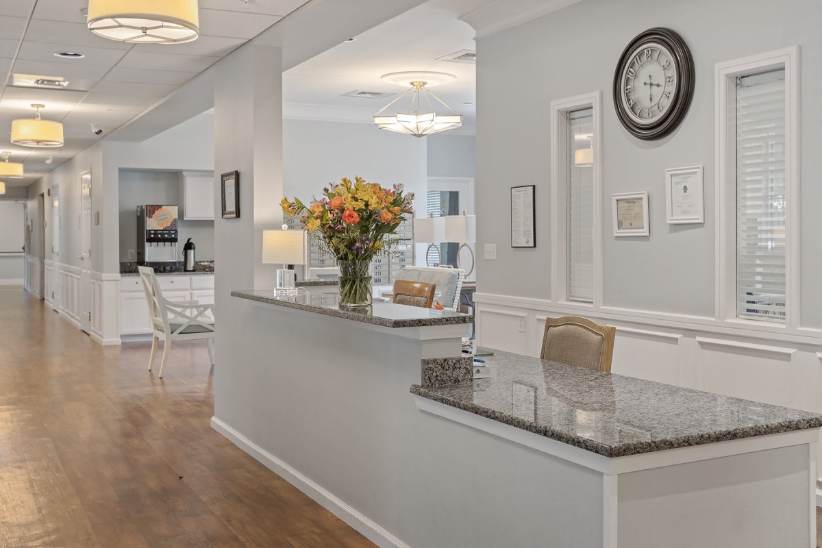 A modern and stylish kitchen with neutral tones, featuring a floral centerpiece and a wall-mounted clock.