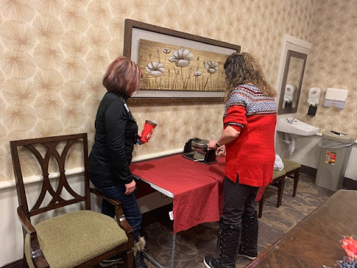 Two individuals engaged in a discussion or activity at a table covered with a red cloth.