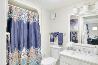 A neatly organized bathroom with a colorful shower curtain and matching towels.