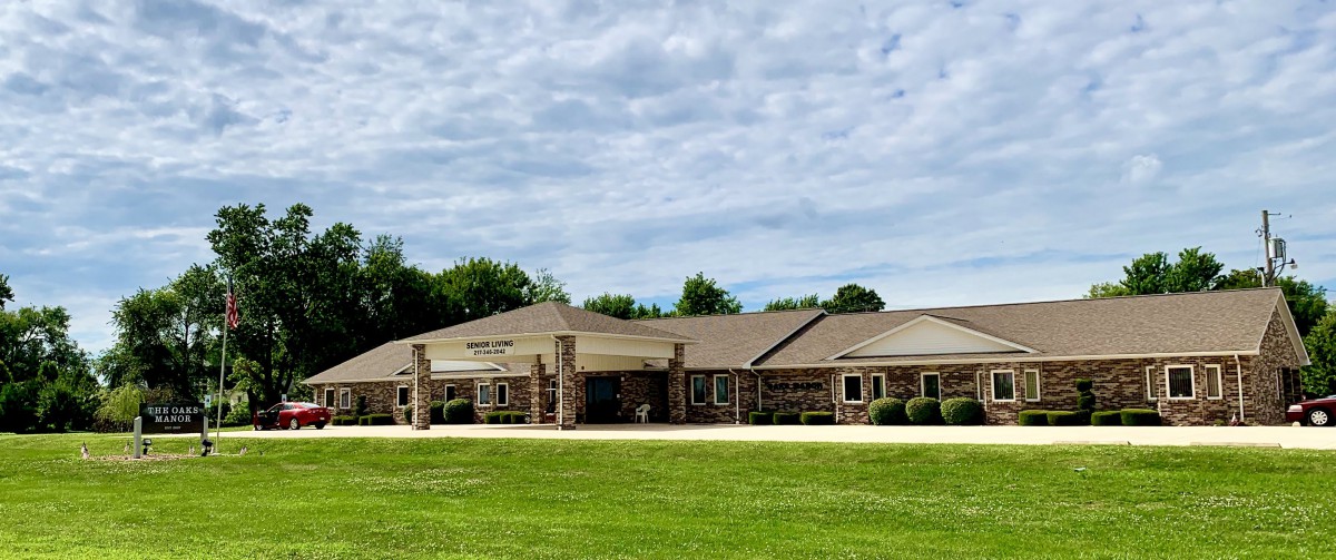 A large building surrounded by a green lawn under a partly cloudy sky.