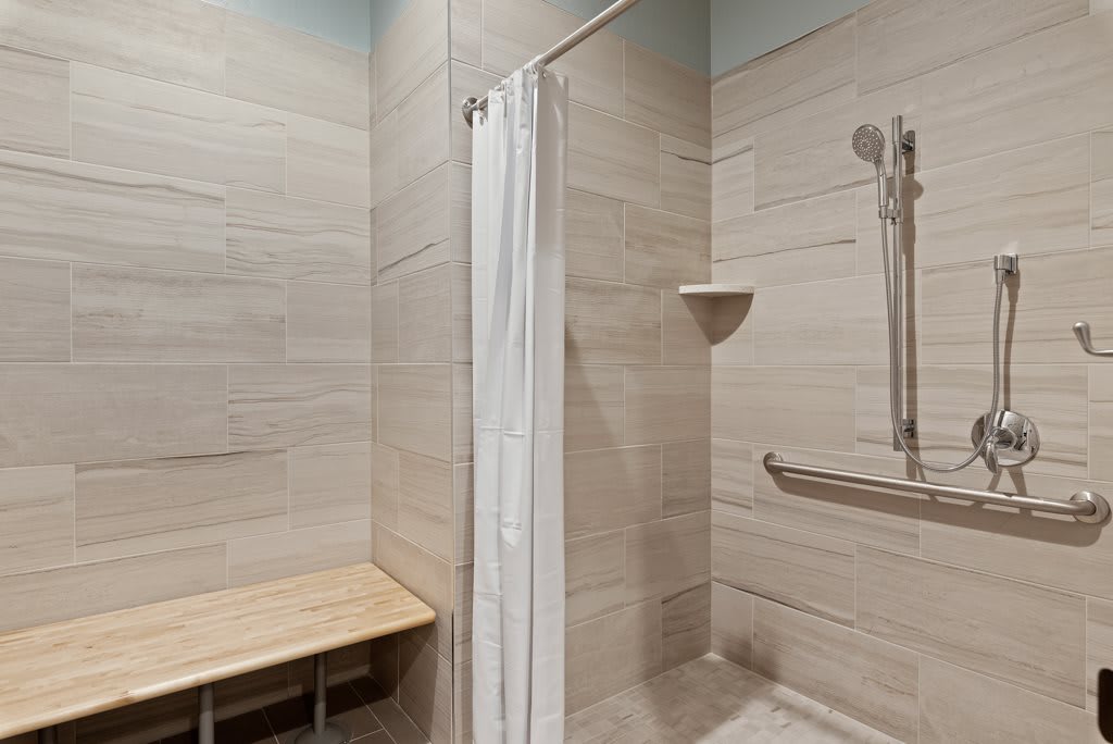 An accessible shower with a bench and grab bar.