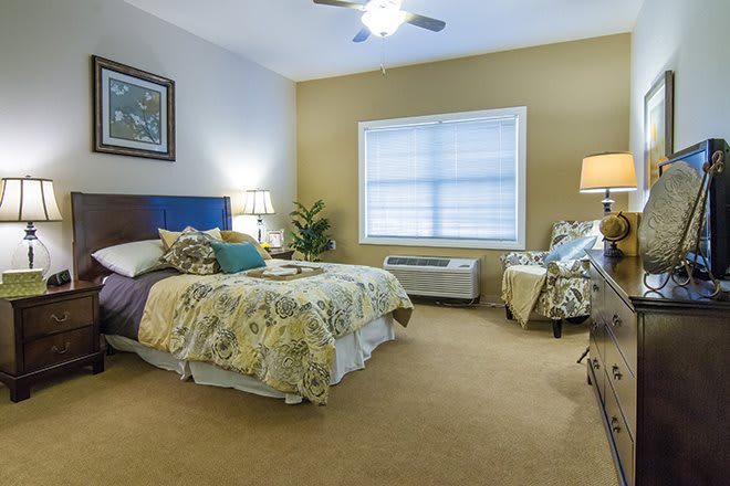 A cozy bedroom with modern decor, featuring a comfortable bed, bedside tables with lamps, and a large window providing natural light.