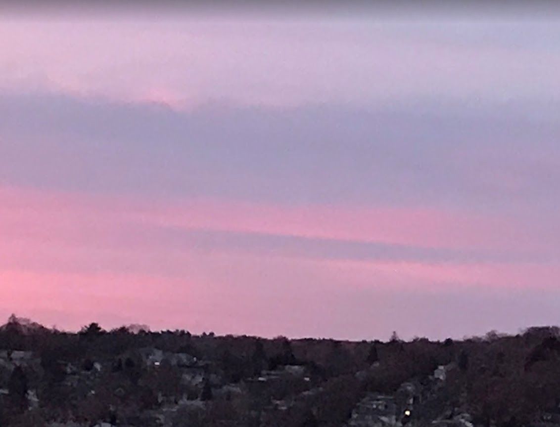 A serene sunset with pink and purple hues in the sky over a dark landscape.