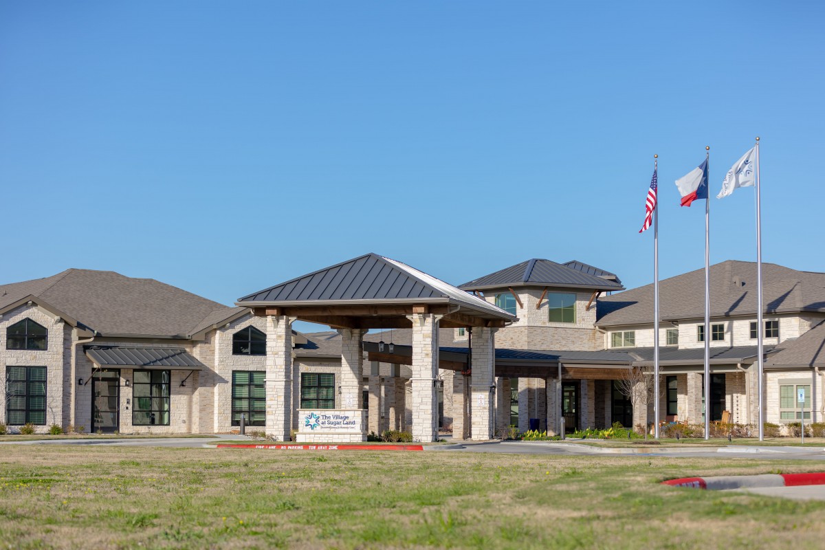 A modern healthcare facility with an entrance and flags displayed outside.