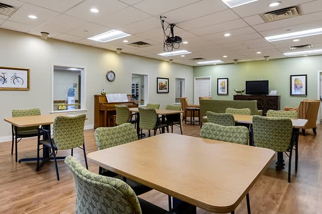 A well-lit meeting room with tables, chairs, and a ceiling-mounted projector.