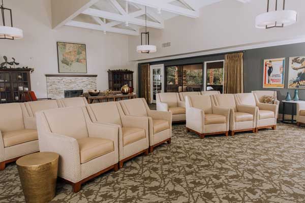 A modern lobby with beige armchairs and a patterned carpet.